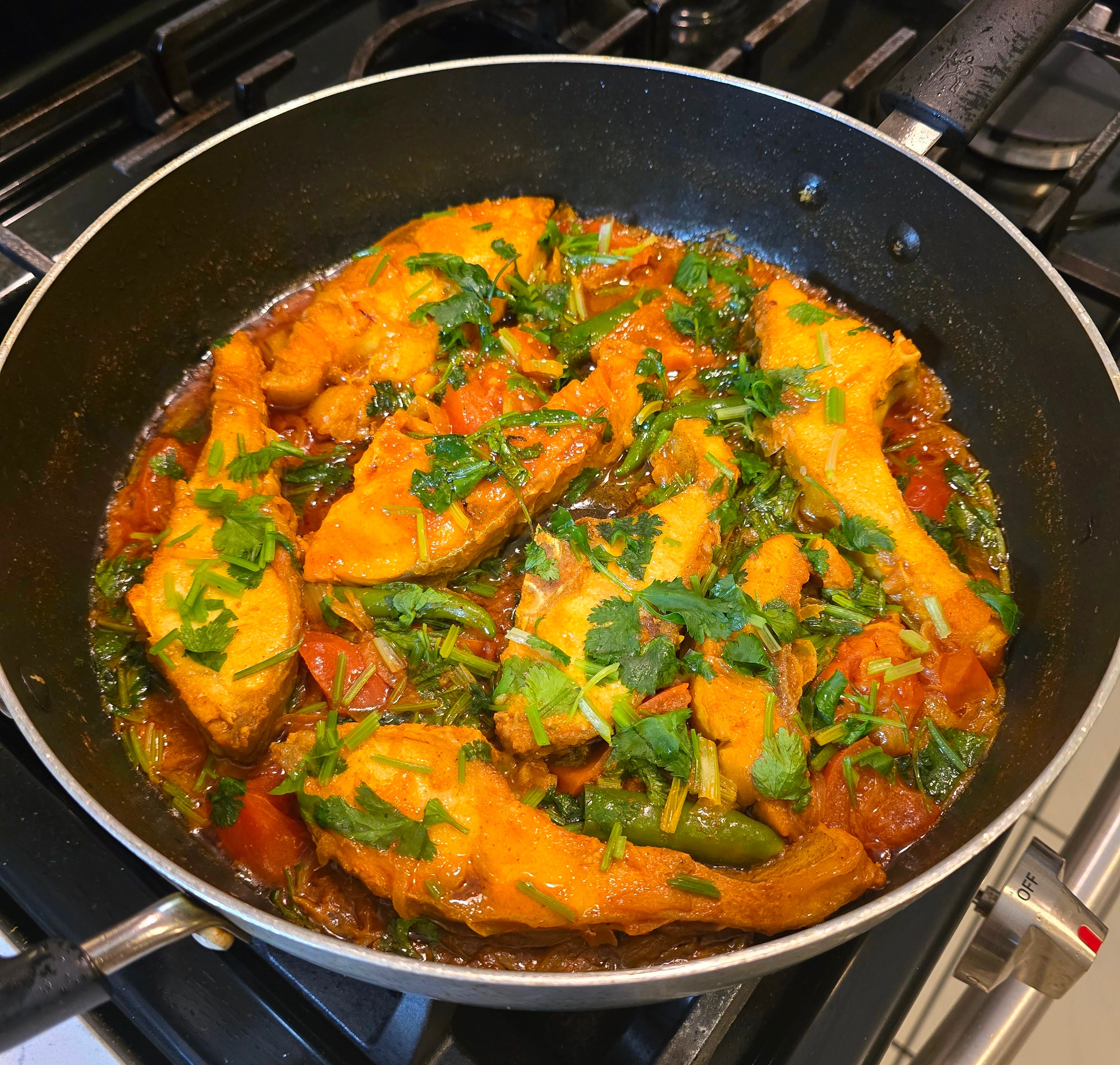 Rui fish bhuna cooked in a pan with tomato and coriander